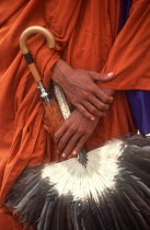 Pochentong Airport.  Buddhist monk  detail of hands  robes  umbrella and fan.