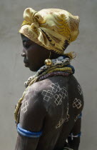 Portrait of a Dipo girl dressed in venetian beads and gold earrings for her puberty initiation with painted crosses on her back and a headscarfAfrican Ghanaian Western Africa One individual Solo Lone...