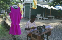 Dressmaker working outside at hand operated sewing machine.