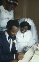 Ibo wedding ceremony.  Couple in traditional western wedding dress signing register.Igbo