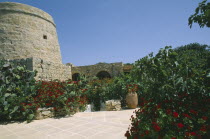 Entrance to Ta  Cenc Hotel with traditional grain store and lined with flowers.