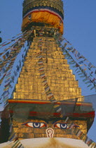Detail of spire of stupa with painted eyes and hung with prayer flags.