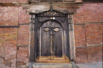 Hanuman Dhoka  the old royal palace in Durbar Square.  Detail of medieval carved wooden door in red brick wall.