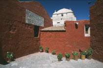 Alleyway with brightly coloured buildings and the white roof of the Monasterio de Santa Catalina beyond Colored