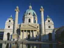Karlskirche aka Church of St Charles Borromaeus. View of the facade showing twin columns and domed roof with pool in the foreground