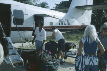 Passenger plane with tourists on runway unpacking luggage.