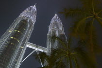 Angled view looking up at the Petronas Towers at dusk.