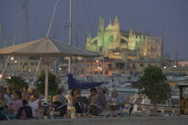 Waterfront cafe at dusk in Palma de Mallorca with La Seo Cathedral in the background.Mallorca