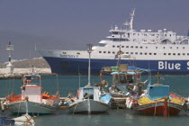 Passenger ferry in port with colourful fishing boats in the foreground. Colorful