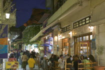 Street cafes in Plaka at dusk with the Acropolis in the background.