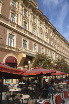 Street cafe with tables and chairs under large red umbrellas