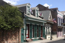 French Quarter. View along row of houses with green shuttered windows and flying flags