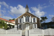 Small brick church with white shuttered windows and surrounding picket fence