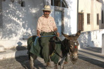 Man on the back of a donkey in the streetThira
