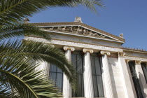 Angled view of the National Academy columned facade partially obscured by palm fronds