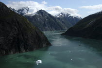 View over rocky cliff edged waterway toward mountain peaks