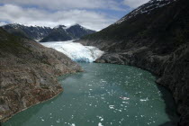 View along waterway toward icy slope and mountain peaks beyond