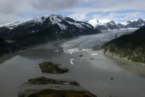 View over murky waters and valley leading toward snowcapped mountain peaks