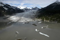 View over murky waters and valley leading toward snowcapped mountain peaksGlacier