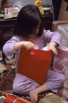 Five year old girl sitting on the floor opening her Christmas presents