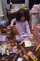 Five year old girl sitting on the floor opening her Christmas presents