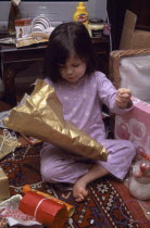 Five year old girl sitting on the floor opening her Christmas presents
