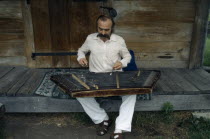 Man playing zither like instrument called a dulcimer.