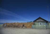 Buryat house with large stack of firewood at side.