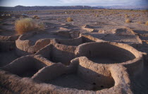 Excavated village dwellings in desert landscape.