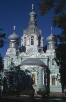 Pale green and white painted exterior facade of Ukrainian Orthodox Church with onion dome rooftops.
