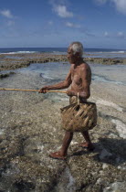 Atiu.  Lagoon fisherman with bamboo rod and woven basket.