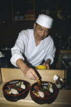 Sushi chef preparing dish.