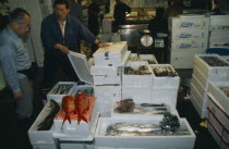 Tsukiji Market.  Fish buyers looking at fish packed in ice for sale.
