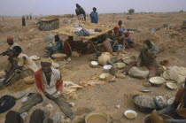 Gold miners working above ground in barren landscape.