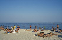 People sunbathing on sandy beach beside the Black Sea.