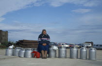 Woman sitting on milk cans waiting for ferry.