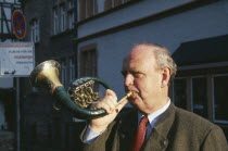 Man blowing hunting horn in town in the Mosel Valley.
