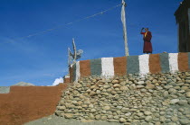 Monk standing on painted terrace of Tsarang s temple.