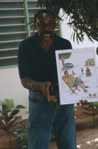 Male teacher using story boards to demonstrate AIDS awareness and safe sex message.