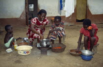 Woman with children cooking Abenkwan or palm nut soup a thick broth made from the pulp of boiled palm fruit with added fish or meat and spices.