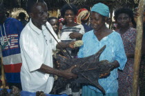 Man purchasing dried grasscutter  a type of large rodent  from woman on market stall.money transaction  buying