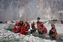 Kirghiz woman and children laughing as they wash pots in fresh water mountain stream.