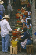Girls selling fruit and vegetables on stone steps of market.