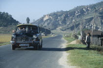 Packed ambassador taxi on road through rural area in north east India.