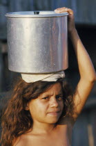 Young girl carrying pot of water on her head. Brasil