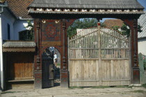 Woodcarvers house with elaborately carved gateway decorated with plant and bird motifs.