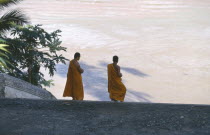 Two monks on steps leading down to river.