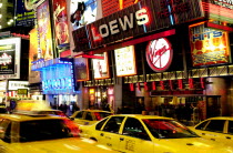 Times Square illuminated at night with passing yellow taxi cabs
