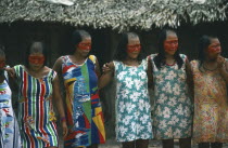 Xikrin Indian women with the tops of their heads shaved and their faces painted with red urucu juice but wearing western style dress.Brasil Kaiapo Kayapo Brazil Mebengorke