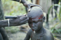 Dinka initiation into manhood.  Scarring ceremony in which each boy has six horizontal lines cut into his forehead  any sign of weakness brings dishonour.  Practice now carried out less often